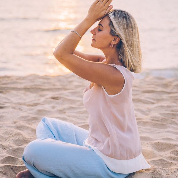 Woman meditating peacefully in a natural outdoor setting at sunrise.